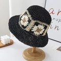 Black woven straw bucket hat with beige floral pattern on a wooden hat stand - One Size / Black