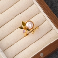 Detailopname van gouden ring met roze parel en emaille bloemmotief in geschenkdoos - Roze barokke parel bloem ring(NL00663R)