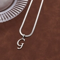 Silver snake chain necklace with polished letter G pendant on brown suede background - Letter G