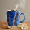 Ceramic coffee mug with blue bark texture and stainless steel rim on wooden base - Blue