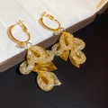 Dettaglio ravvicinato di orecchini dorati con foglie e zirconi su portagioie - Oro (Perno in argento sterling 925)