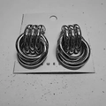 Three-layered overlapping silver metal hoop earrings on white jewelry display card - 22X32 Silver Style