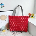 Red canvas tote bag with white anchor print and grey handles on a white table - Anchor Red