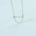Primer plano de collar minimalista plateado con colgante de corazón hueco fino - Color Acero