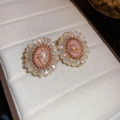 Detailopname van vintage bloemoorbellen met roze kristallen in een sieradendoosje - Goud