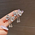Détail de boucles d'oreilles à pompons argentées avec nœud en cristal et strass brillants - Gland en Nœud Papillon Argenté (028)
