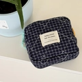 Detailed shot of a navy blue checkered quilted pouch with an orange zipper and tassel - Blue