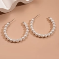 Vista macro de grandes pendientes de aro con elegantes perlas blancas y agujas de plata - Aro grande con perlas grandes