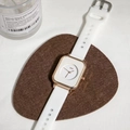 Dettaglio dell'orologio quadrato dorato con cinturino in silicone bianco su feltro - Bianco