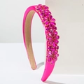 Detail eines rosenroten Haarreifens mit funkelnden Kristallblumenmustern auf Samtstoff - Fuchsia