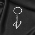 Polished silver stainless steel letter V keychain pendant on dark fabric background - Letter V