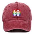 Close-up detail of the rainbow LOVE embroidery on a red washed distressed baseball cap - One Size / Burgundy