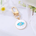 Detail eines bösen Blicks Schlüsselanhänger mit blauem Emaille und goldenen Wimpern - Weißes Wimpern-Emaille-Auge