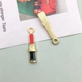 Macro detail of red enamel lipstick charms with golden textured back and top rings - Lipstick (10985)