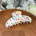 Macro shot of colorful terrazzo acetate hair claw clip on a rustic wooden tray - Candy Palette