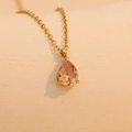 Close-up of golden necklace with a teardrop champagne pink gemstone pendant - March (Champagne)
