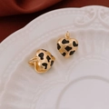 Vista macro de pendientes de corazón con borde dorado y esmalte de manchas negras en plato - Estilo de Corazón con Patrón de Vaca (14#耳扣-金色)