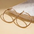 Primo piano di grandi orecchini a cerchio dorati classici su un supporto di marmo - 4cm / Oro