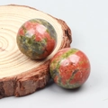 Polished Unakite crystal sphere set with green and pink stone textures on wood base - Unakite
