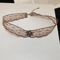 Dettaglio choker vintage in pizzo marrone con ciondolo floreale e chiusura a moschettone - Stile Fiore Nero