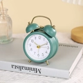 Detailopname van een vintage groene metalen wekker met gouden handvat op een boek - Groen