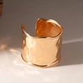 Details der Hammerschlag-Textur und des goldenen Metall-Finishs des breiten Armreifs - Gold