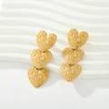 Macro view showing the hammer-textured surface of the triple heart golden drop earrings - Triple Hammered Heart
