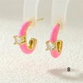 Dettaglio di orecchini a lobo in smalto rosa a forma di C con base dorata e zircone bianco - Rosa