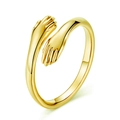 Macro shot of gold-plated embrace ring showing smooth metallic texture and hugging hands - Style 001 / Gold