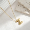 Close-up of gold 3D balloon letter Z pendant necklace on minimalist stone background - Letter Z