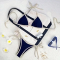 Two-piece navy blue bikini with beige trim, halter neck top and side-tie bottoms on beach mat - Dark Blue