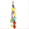 Dettaglio portachiavi bohémien con perline di legno colorate, pompon e nappe - Giallo