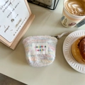 Mini borsa per cosmetici in maglia a righe con etichetta ricamata in un ambiente café - Peluche Arcobaleno Rosa