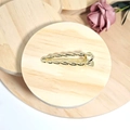 Detailed close-up of golden twist rope metal hair clip on a wooden display stand - Gold Twist