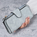Long light blue frosted wallet for women with buckle and zipper held by hand - Blue