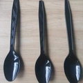 Three black disposable plastic spoons with diamond pattern handles on wooden background - Black Spoons