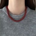 Detail of red beaded necklace worn over a grey sweater for a vintage French style look - 7mm / Red