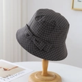 Detail of grey plaid bucket hat featuring a side bow decoration on a wooden stand - Dark Grey Plaid