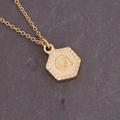 Detailed macro view of a gold hexagonal pendant with a textured letter Q on rock background - Letter Q (17#Q)