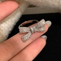 Adjustable silver bow ring with zircon pavé stones shown in a lifestyle finger close-up - Silver