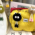 Bunte Plüsch-Rußmonster-Anhänger mit langen Beinen an gelben und weißen Taschen präsentiert - Schwarz