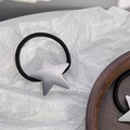 Close-up of a silver brushed metal star hair tie on a white pleated artistic background - Silver