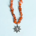 Irregular orange stone bead necklace with a silver sun pendant on a blue background - Red Agate Sun