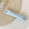 Close-up of blue checkered fabric cable organizer with pink bow and colorful buttons - Blue Gingham Bow