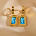 Detailansicht goldener geometrischer Ohrringe mit himmelblauen rechteckigen Zirkonia - Blau