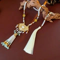 Detalle de collar vintage con perlas y jade sobre una base de madera rústica - Blanco/Amarillo