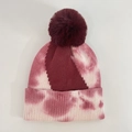 Close-up of pink and burgundy tie-dye knit beanie with fluffy faux fur pompom detail - Burgundy