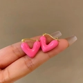 Nahaufnahme von rosa Herz-Ohrsteckern mit goldenem Metallsockel auf dem Finger präsentiert - Rosa Tropföl Herz Hoop Stil (83#)