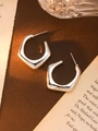 Close-up of irregular silver geometric C-shape acrylic earrings on a vintage book - Silver Open Pentagon