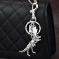 Silver dinosaur skeleton keychain with metal hook accessory hanging on a black bag - Silver